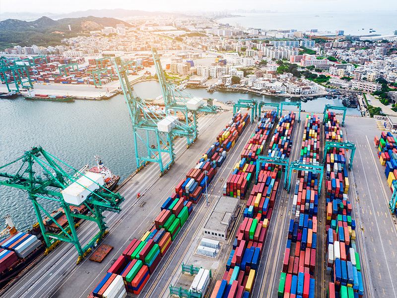 Container terminal with stacked shipping containers where forklift container loading and unloading is staged